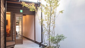 A narrow pathway leading to a wooden building entrance with a small garden area and a tree. - Nijojo Taiken Inn (Kyoto)