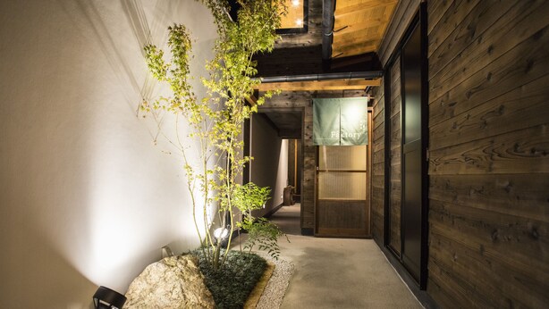 A narrow corridor with a wooden wall on one side and a white wall on the other, leading to a room labeled "Factory." - Nijojo Taiken Inn (Kyoto)