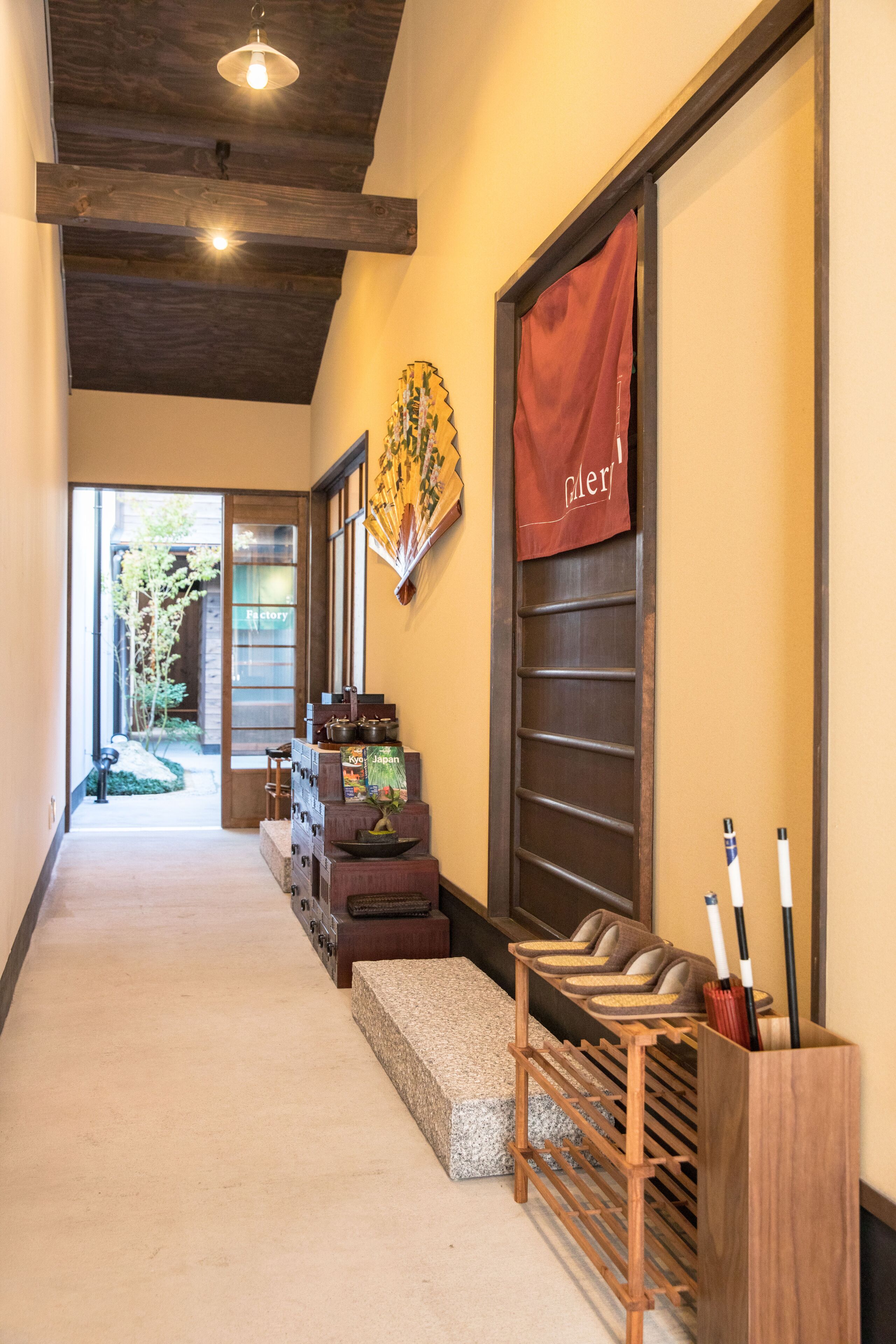 A hallway with a wooden ceiling, a red banner, a display of golf clubs, and a view of a garden outside.