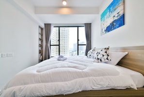 A modern hotel room with a large bed, a city view through a window, and a painting on the wall.
