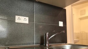 Eine Küche mit Spülbecken aus Edelstahl, einer strukturierten Spritzschutzwand und einer Holz Arbeitsplatte.