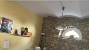 Ein Essbereich mit Steinsäule, Holztisch, weißen Stühlen, einer Hängeleuchte und einem Regal mit Pflanzen und einer Speisekarte.