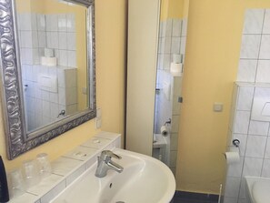 A bathroom with a white sink, a mirror with an ornate frame, and a yellow wall.