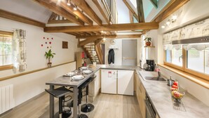 Una cocina funcional con vigas de madera, un comedor y un refrigerador pequeño.