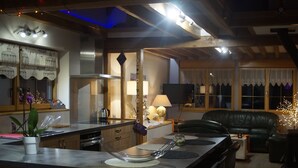Una cocina moderna con zona de comedor, vigas de techo de madera y un sofá de cuero negro.
