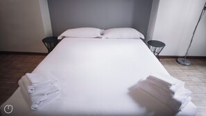 A neatly made bed with pillows and folded towels, two bedside tables, and a floor lamp in a hotel room. - Italianway Easy - Corso Como 8 (Milano)