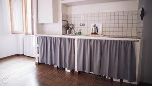 A kitchen with a grey curtain, white tiles, and a window with blinds. - Italianway Easy - Corso Como 8 (Milano)