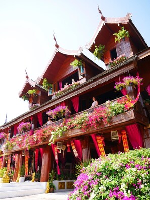A traditional multi-story building with balconies adorned with flowers and red drapes.