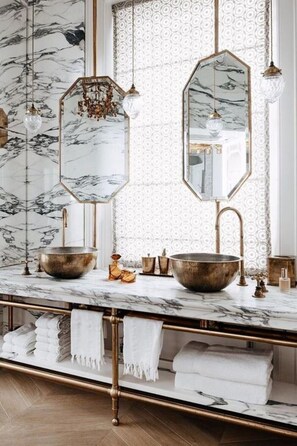 Bathroom features a marble countertop, gold fixtures, and a hexagonal mirror frame.