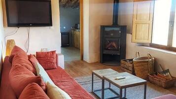 A living room with a sofa, a television, a fireplace, and a window.