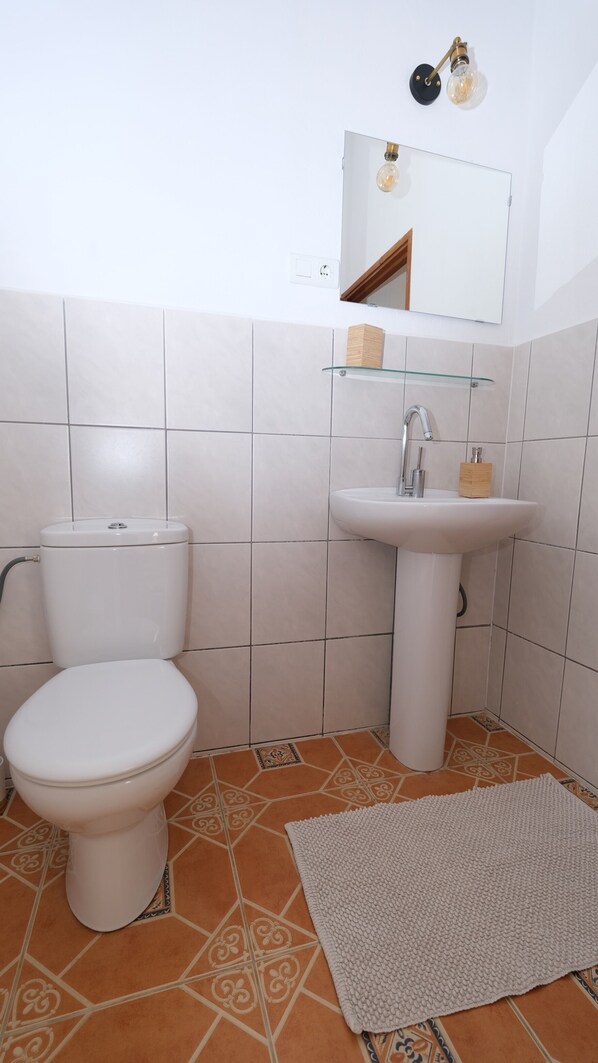 Une salle de bain avec des toilettes, un lavabo et un miroir.