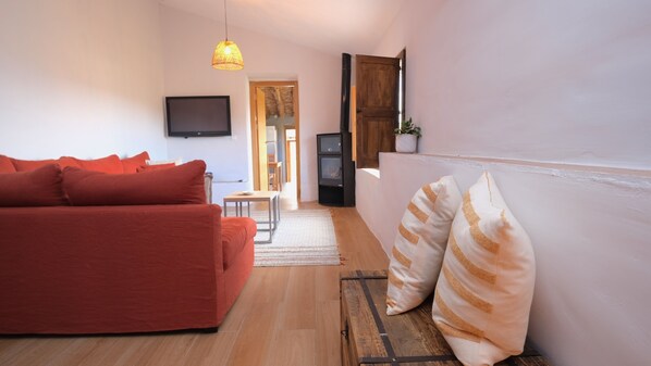 Una sala de estar moderna con un sofá rojo, un televisor y una escalera que lleva a otro nivel.