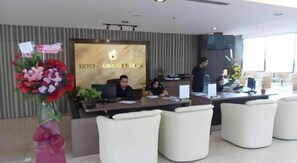 A hotel reception area with a reception desk, seating, and a large floral arrangement. - HOTEL GRAND BARON TAIPNG (TAIPING)
