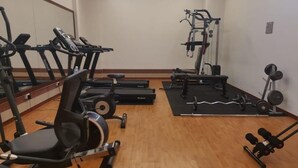 A gym with treadmills, a bench press, and weightlifting equipment. - HOTEL GRAND BARON TAIPNG (TAIPING)