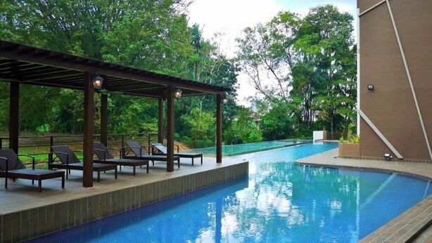 A swimming pool with lounge chairs and a pergola, surrounded by trees. - HOTEL GRAND BARON TAIPNG (TAIPING)