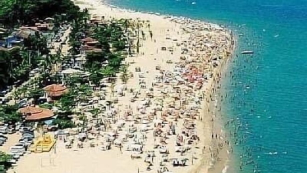 Una playa concurrida, con muchas sombrillas y gente.