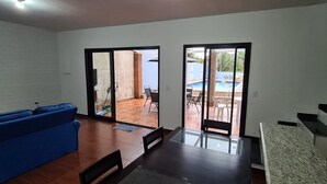 Una sala de estar con un sofá azul, una mesa de vidrio y vistas a un patio con piscina.