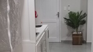 Et moderne køkken med hvide skabe, et køleskab og en potteplante.