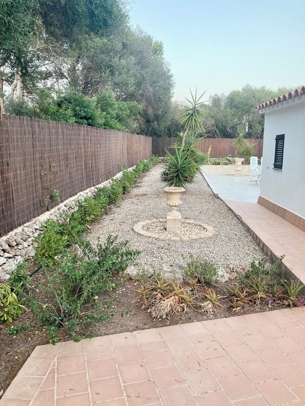 A garden area with a stone planter, gravel paths, and a wooden fence.