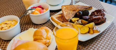 A breakfast table with various food items and beverages.