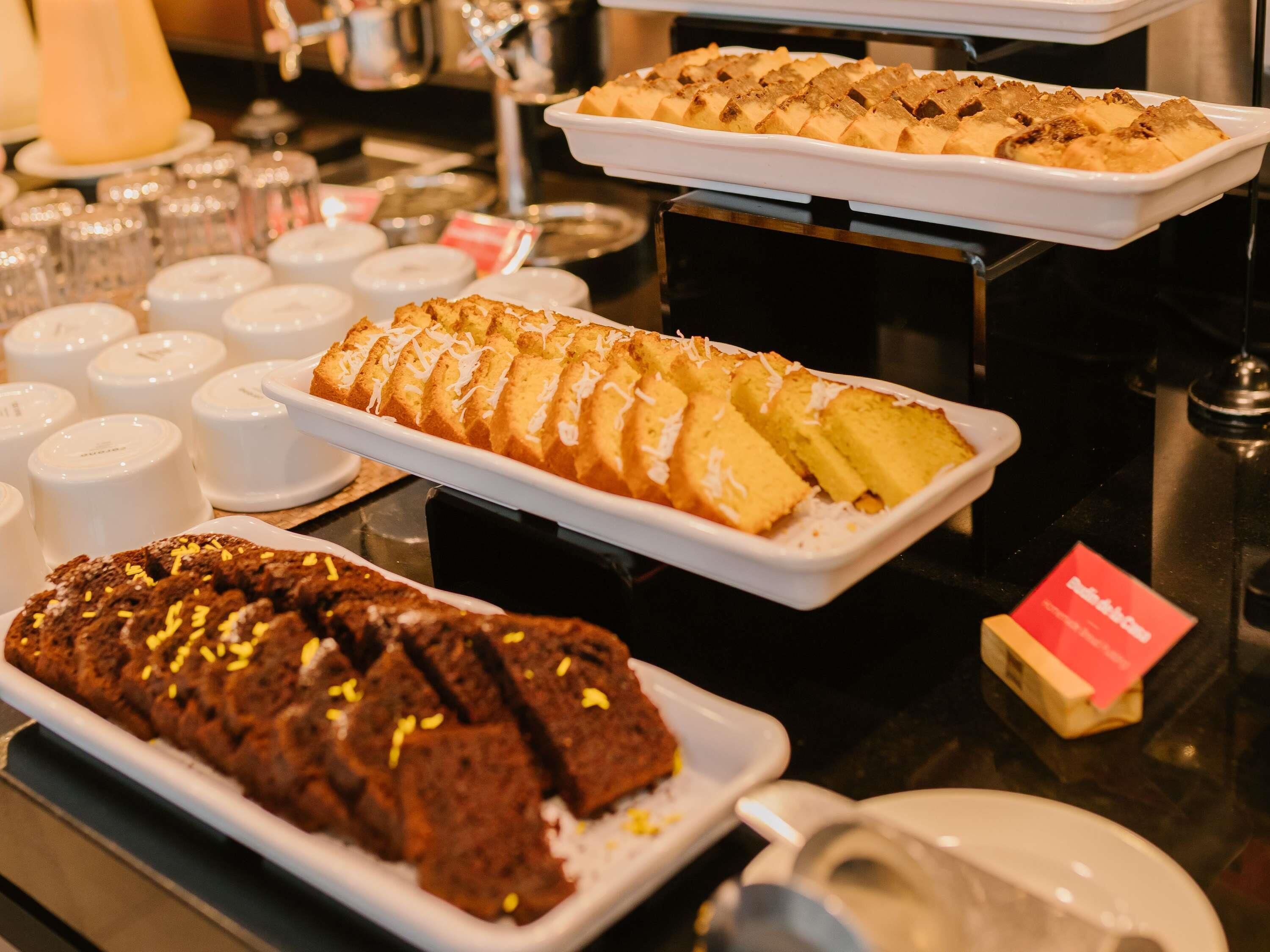 Een buffet met diverse desserts, waaronder een brood, een schaal taarten en een chocoladetaart.