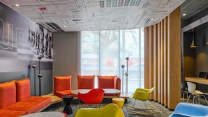 A modern lounge area with vibrant seating, a large window, and a ceiling with artistic designs. - ibis Trujillo (Trujillo)