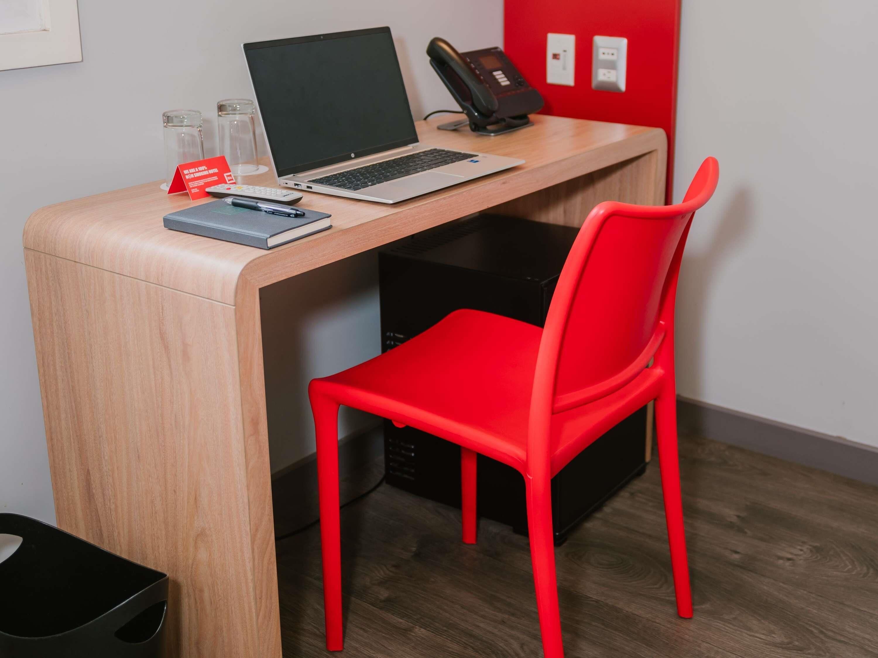 A modern workspace with a laptop, a red chair, and a desk.