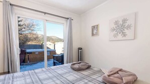 Un dormitorio con una colcha escocesa, dos almohadas, un radiador y una ventana con cortinas.