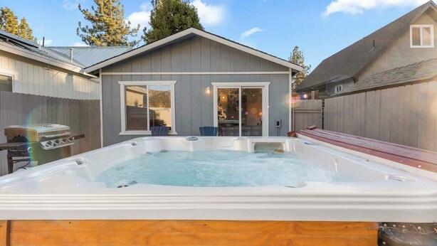 Un jardín trasero con un jacuzzi y un porche cubierto.