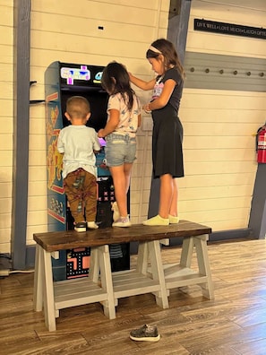 Un banco de madera con un niño y dos adultos de pie junto a una máquina recreativa colorida.