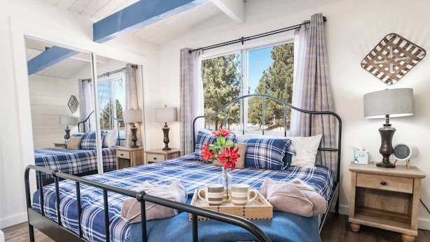 A bedroom with a large bed, a bedside table, a lamp, and a window with curtains.