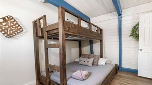 Una cama litera con estructura de madera, colchón gris y almohadas escocesas.