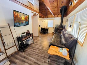 A cozy living room with a leather sofa, a wooden coffee table, a painting on the wall, and a fireplace.