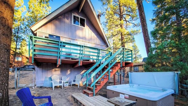 Une cabane en bois dotée d’un bain à remous, d’un espace extérieur aménagé et d’un escalier menant à une terrasse supérieure.