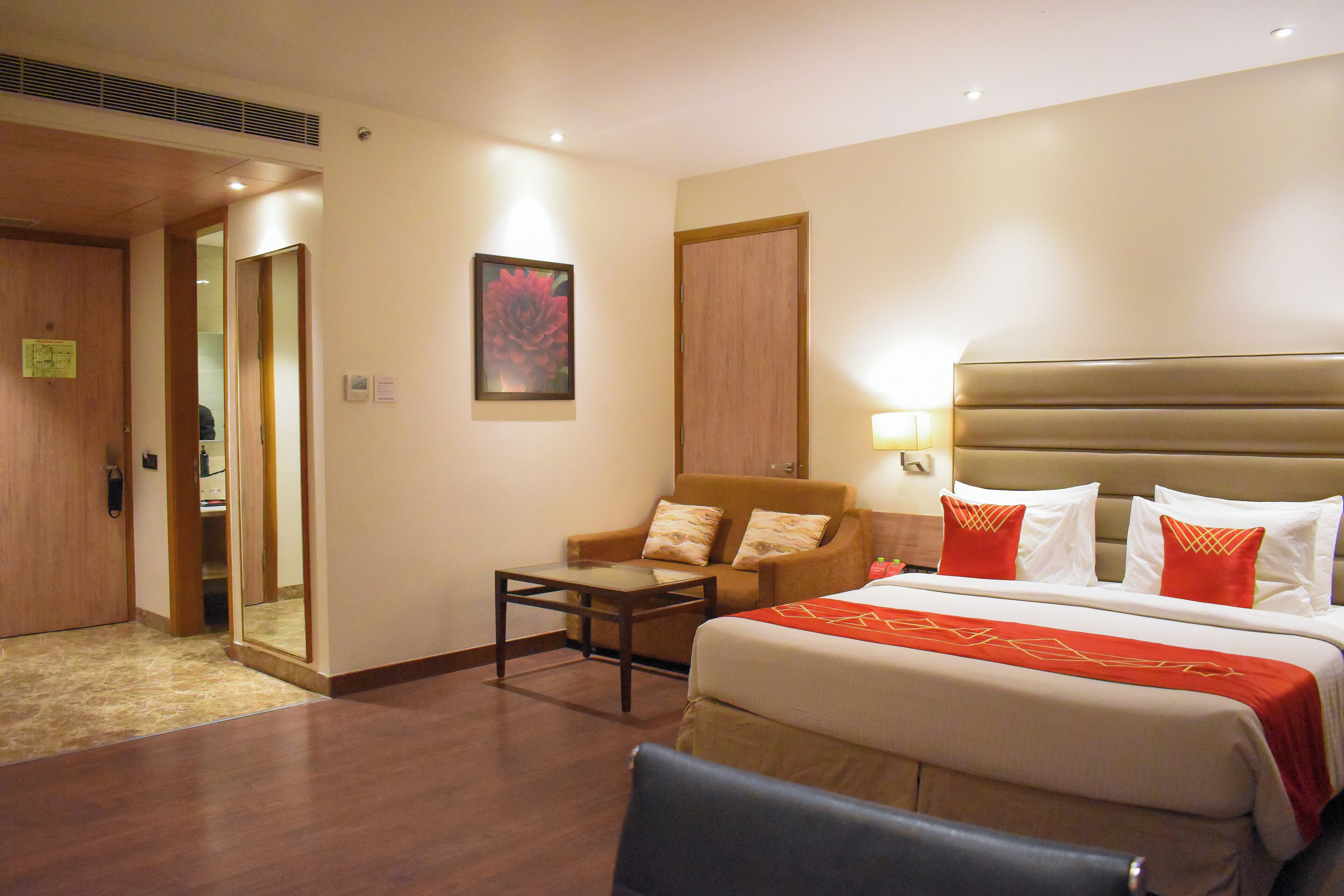 Habitación de hotel con una cama grande, una silla, una mesita y una puerta que da a un armario.