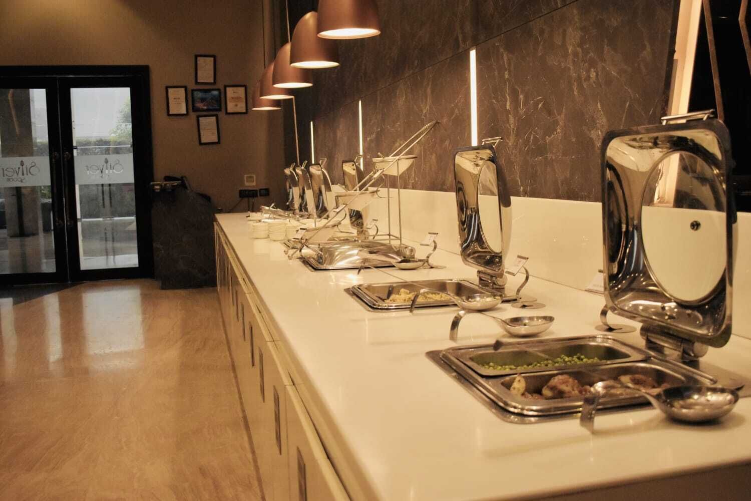 A buffet setup with various food items and utensils on a counter.