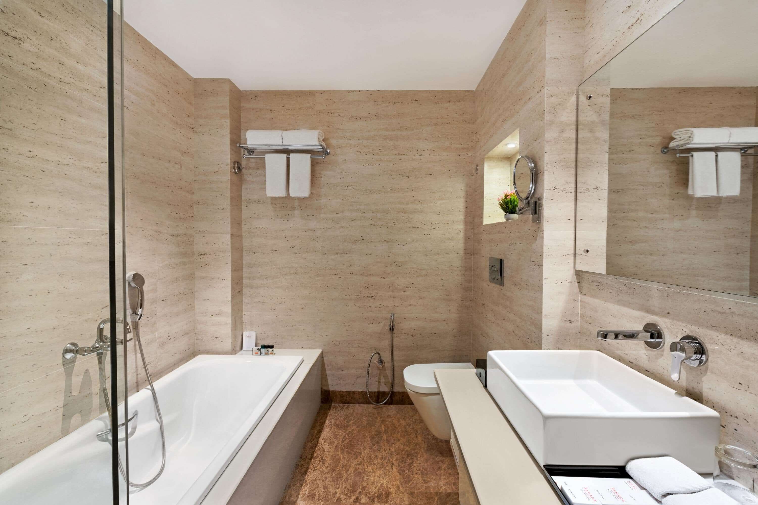 A modern bathroom with a glass-enclosed shower, a white bathtub, a toilet, and a vanity with a mirror.