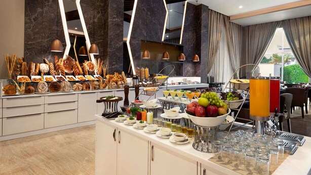 Un espace buffet proposant une variété de plats et de boissons, doté d’un éclairage moderne et offrant une vue sur l’extérieur.