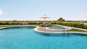 Une piscine avec une terrasse en bois, des chaises longues et un parasol.