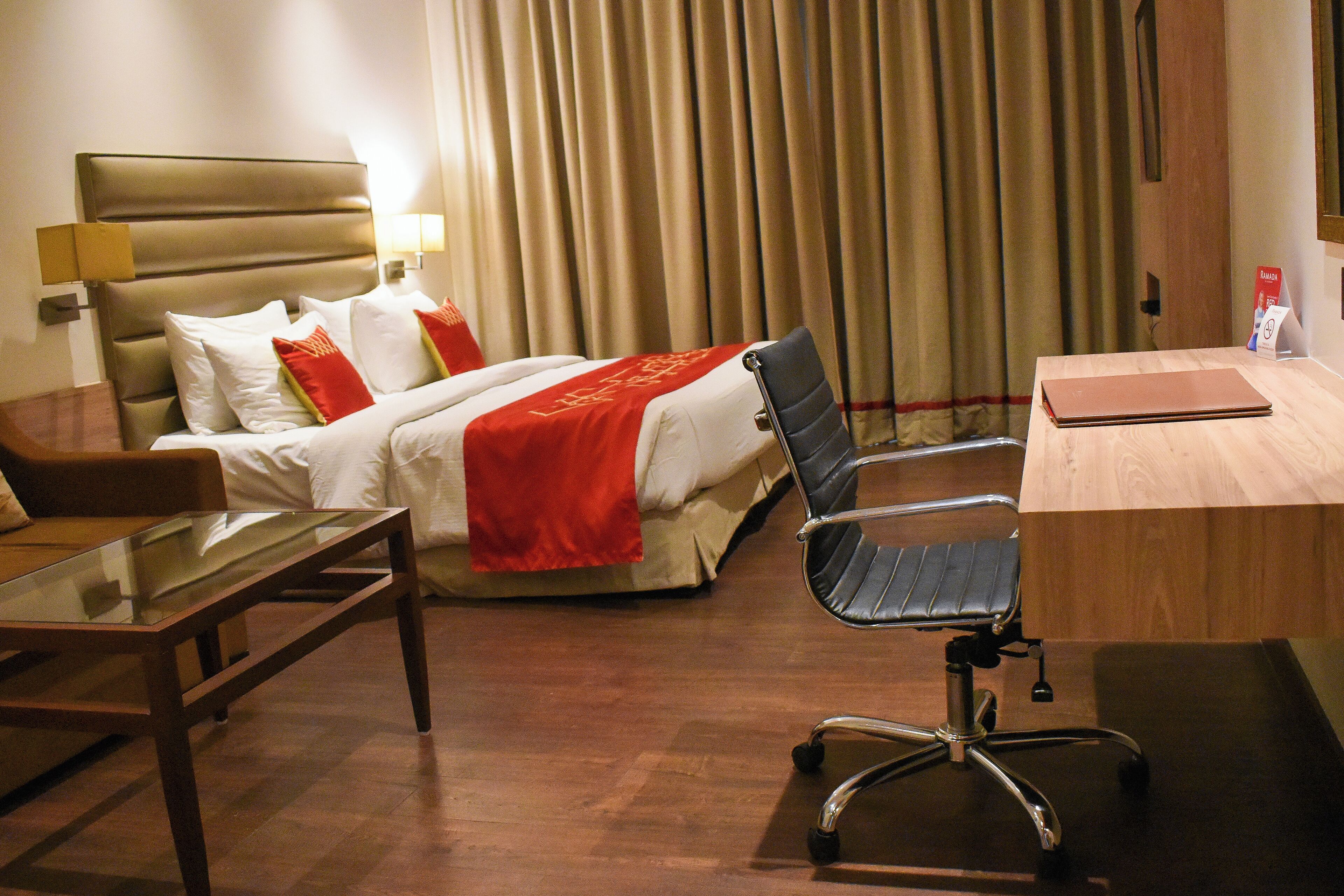 Une chambre d’hôtel avec un lit, un bureau, une chaise et une table en verre.
