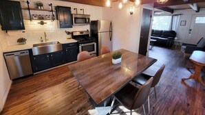 Uma cozinha moderna com piso de madeira, eletrodomésticos de aço inoxidável e iluminação pendente.