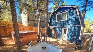 A backyard with a metal table, wooden deck, and a hot tub.