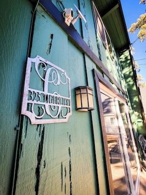 A teal-painted building with a metal sign reading "325 N. Gertrude St." and a small lantern on the wall.
