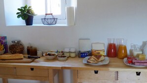 Un plan de travail de cuisine avec divers aliments et ustensiles, notamment une planche à découper, des bols, des bocaux et une bouilloire.
