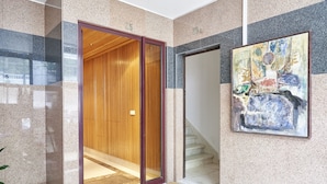 A modern interior with a wooden elevator, a staircase, and a framed abstract painting on the wall. - Campo Pequeno Avenida (Lisbon)