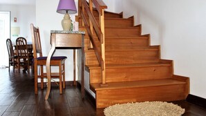 A wooden staircase leading to a landing with a table and chairs. - Great Tranquility Holiday Home (S.Roque do Pico)