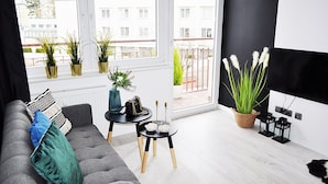 Un salon moderne avec un canapé gris, une table basse noire et des plantes en pot.