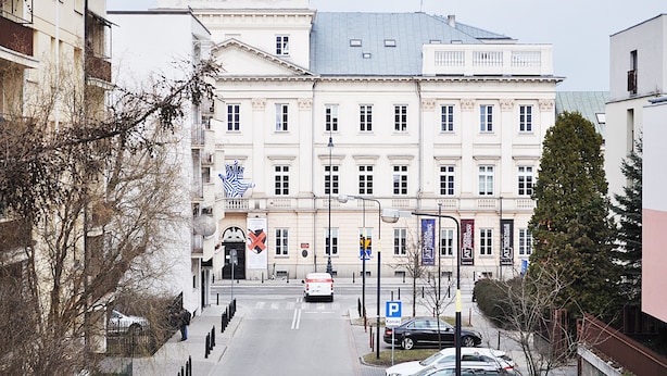 Un grand bâtiment historique, doté d’une entrée imposante, de nombreuses fenêtres et de drapeaux.