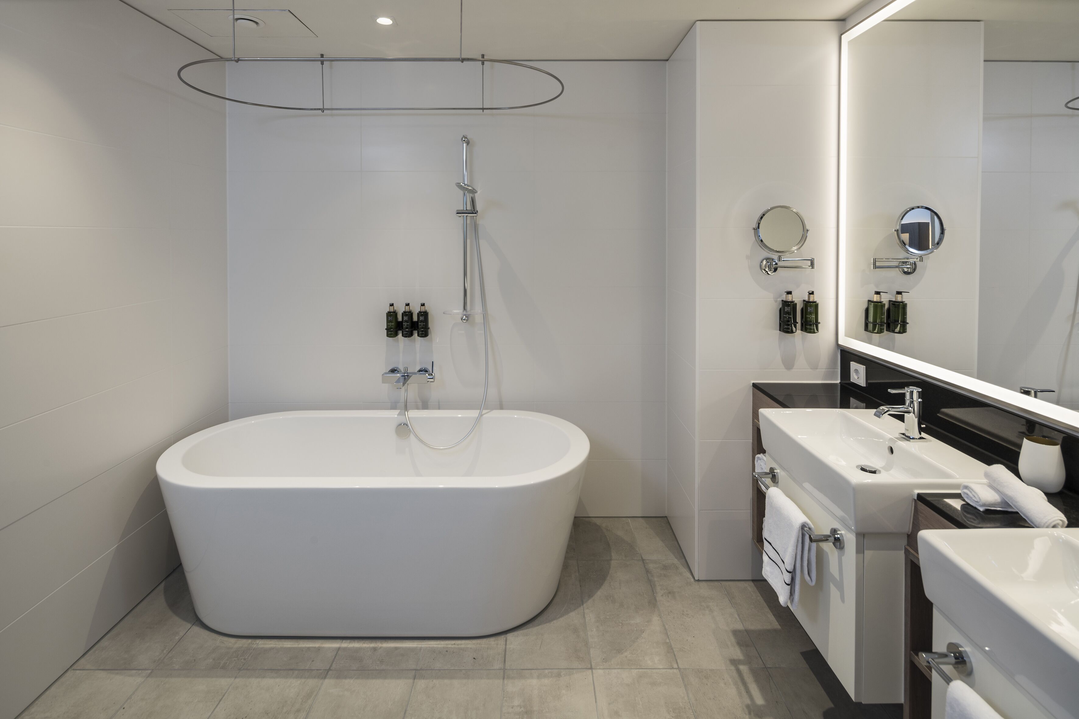 Une salle de bain moderne avec une baignoire sur pieds, un grand miroir et un meuble-lavabo doté d’un évier et d’un porte-serviettes.