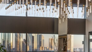Een modern interieur met stadszicht, met een zithoek, een eettafel en hangende hanglampen.